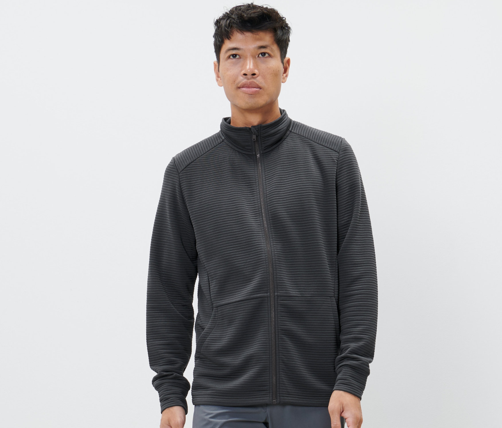 Adam, antrasit renginde bir fonksiyonel ceket giyiyor.