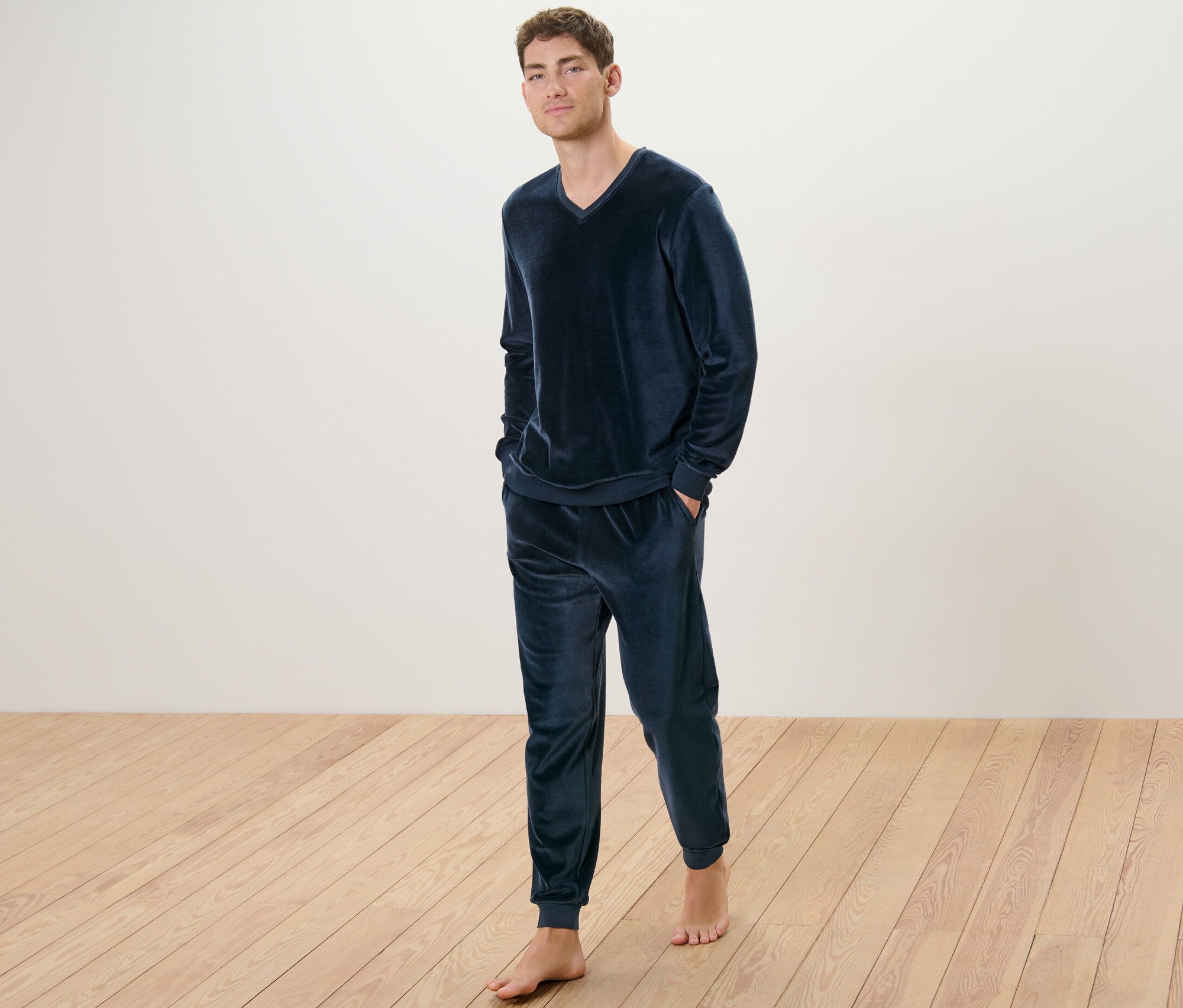 Adam yerde çıplak ayakla duruyor ve üzerinde Niki Pijama Takımı var.