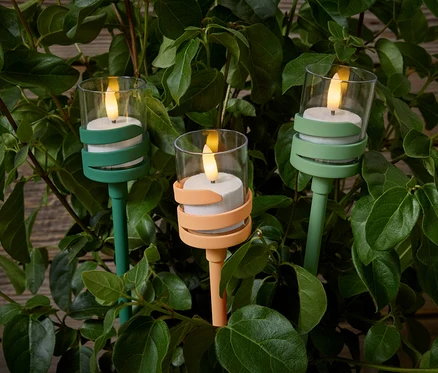 Yeşil yaprakların ortasında üç adet LED'li Outdoor Kazığı. İkisi yeşil, biri şeftali renginde.