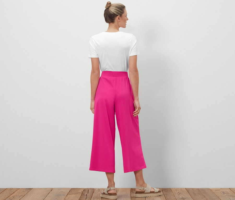 Topuzlu bir kadın kameraya arkası dönük duruyor ve Jersey Culotte Pantolon giyiyor.