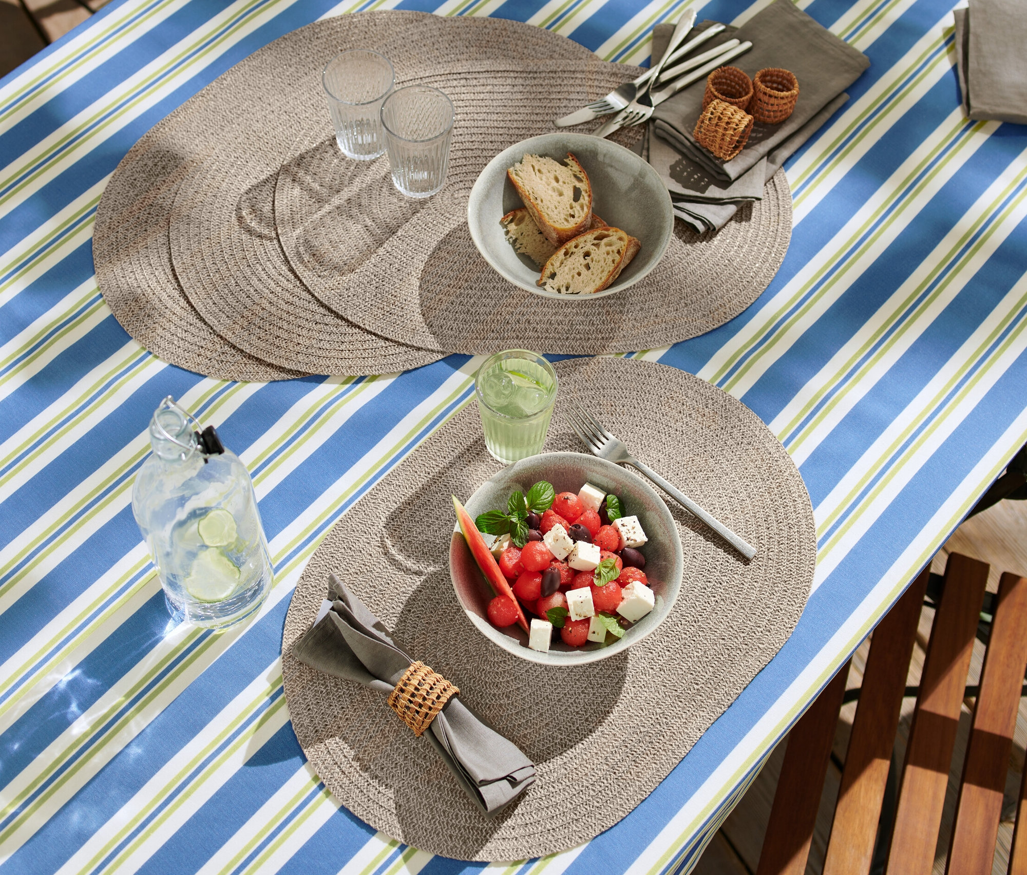 Oval 4 Adet Silinebilir Amerikan Servis ile donatılmış masada salata, ekmek ve içecekler bulunuyor.