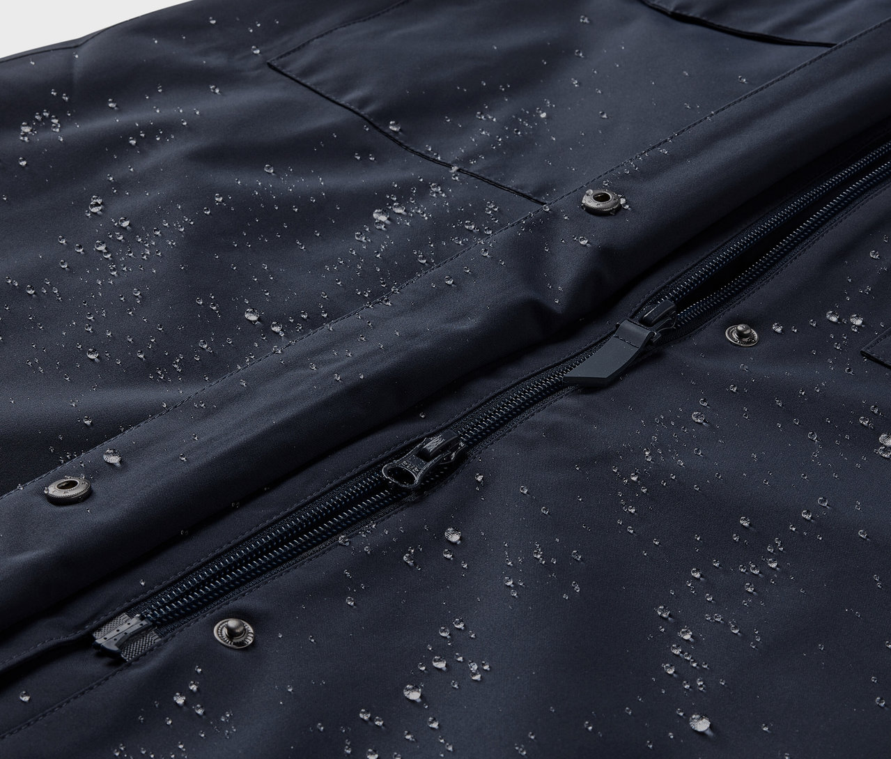 Su damlaları olan yağmurluk trençkotun yakın çekimi.