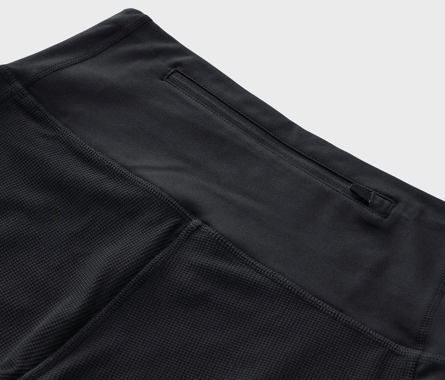 Bel kısmında fermuarlı cebi olan siyah 3/4 trekking taytının yakın çekimi.