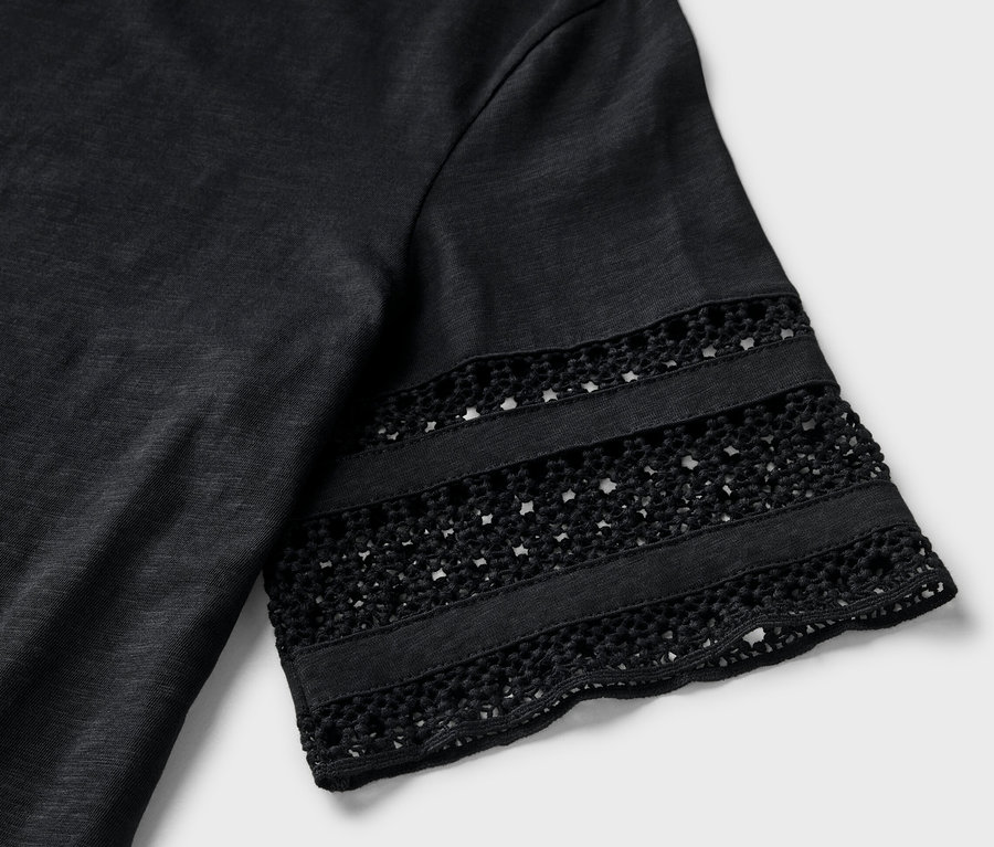 Kol kısmında nakış detayı bulunan siyah tişörtün yakın çekimi..