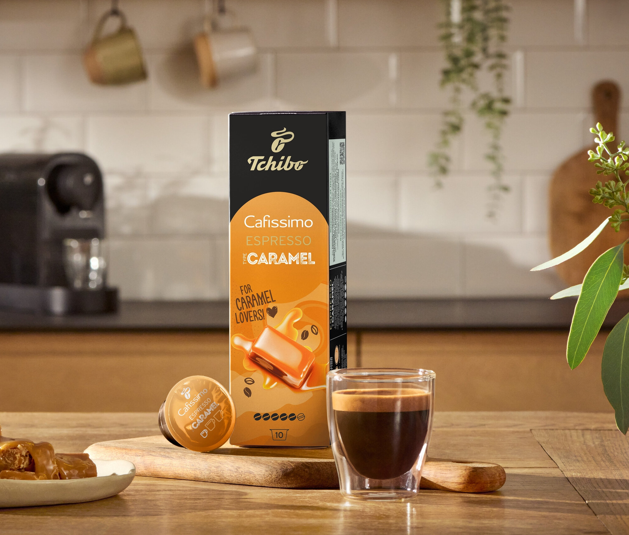 Ahşap bir masa üzerinde bir espresso, karamela şekerlemeleri ve bir paket Flavoured Edition: Espresso Caramel - 80 Kapsül.