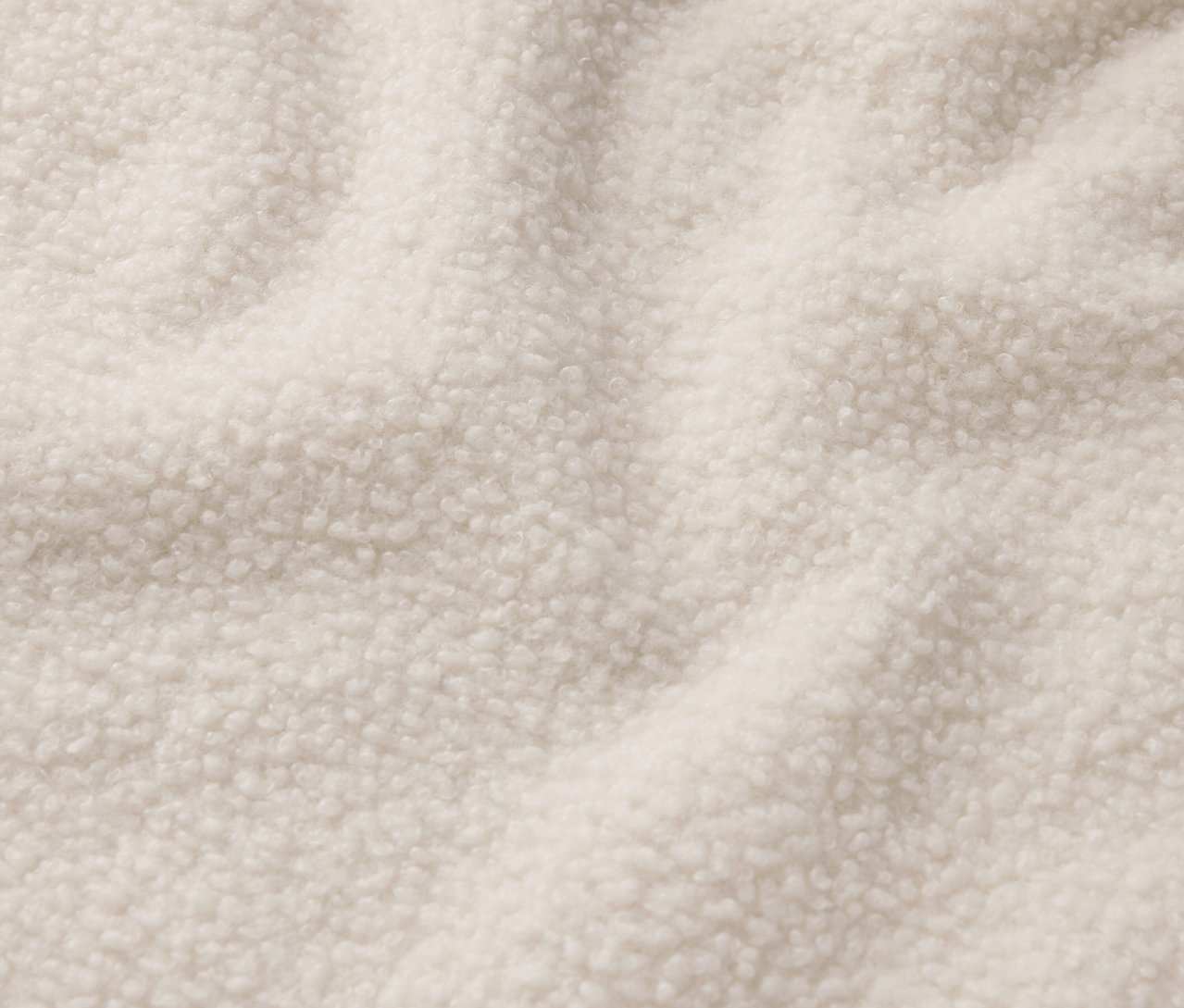 Krem rengi bir shearling kumaşının yakın çekimi.