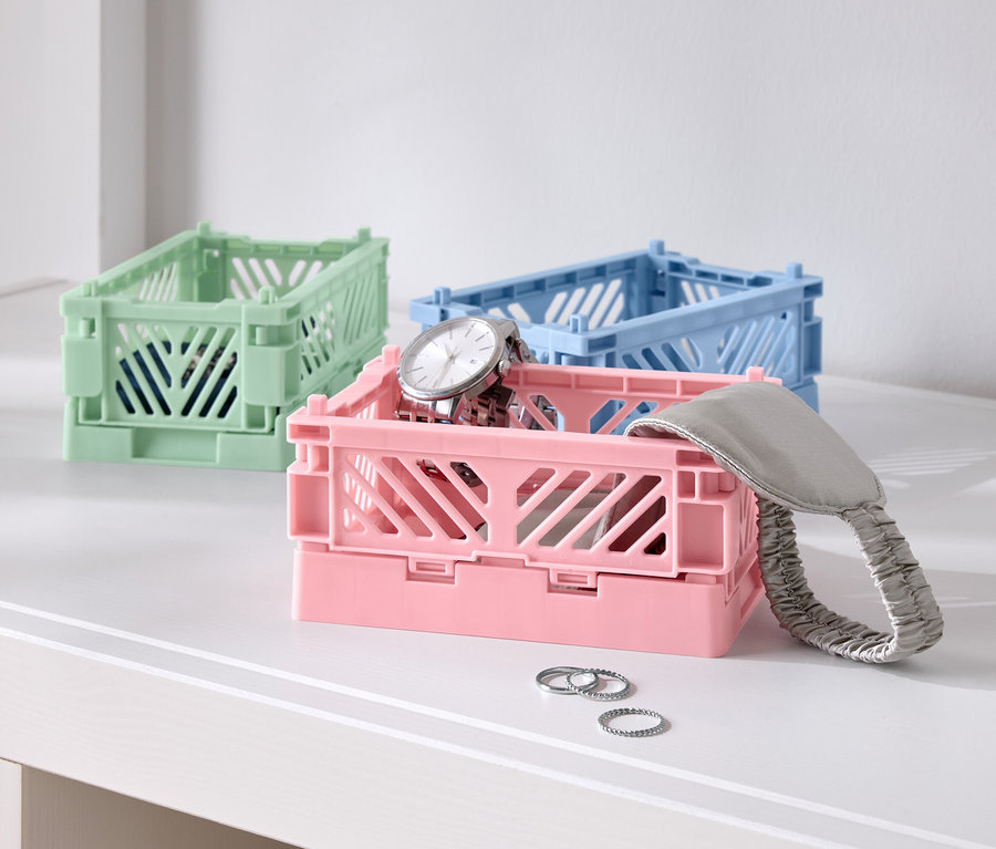 Masanın üzerinde üç renkli katlanır kutu, biri pembe saatli, biri mavi ve biri yeşil.