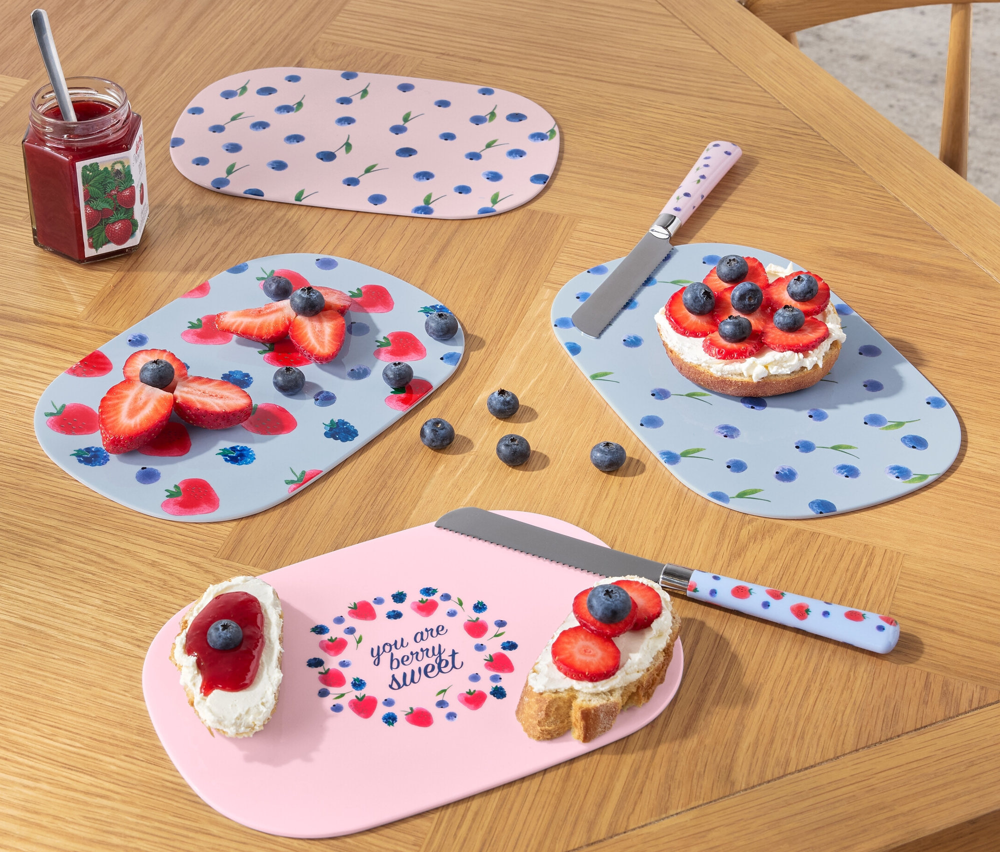 Ahşap bir masanın üzerinde meyve ve bıçaklarla birlikte dört kahvaltı tahtası.