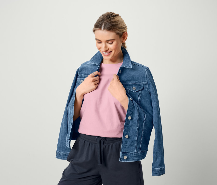 Kadın kot ceket, pembe tişört ve bermuda eşofman altı giyiyor.