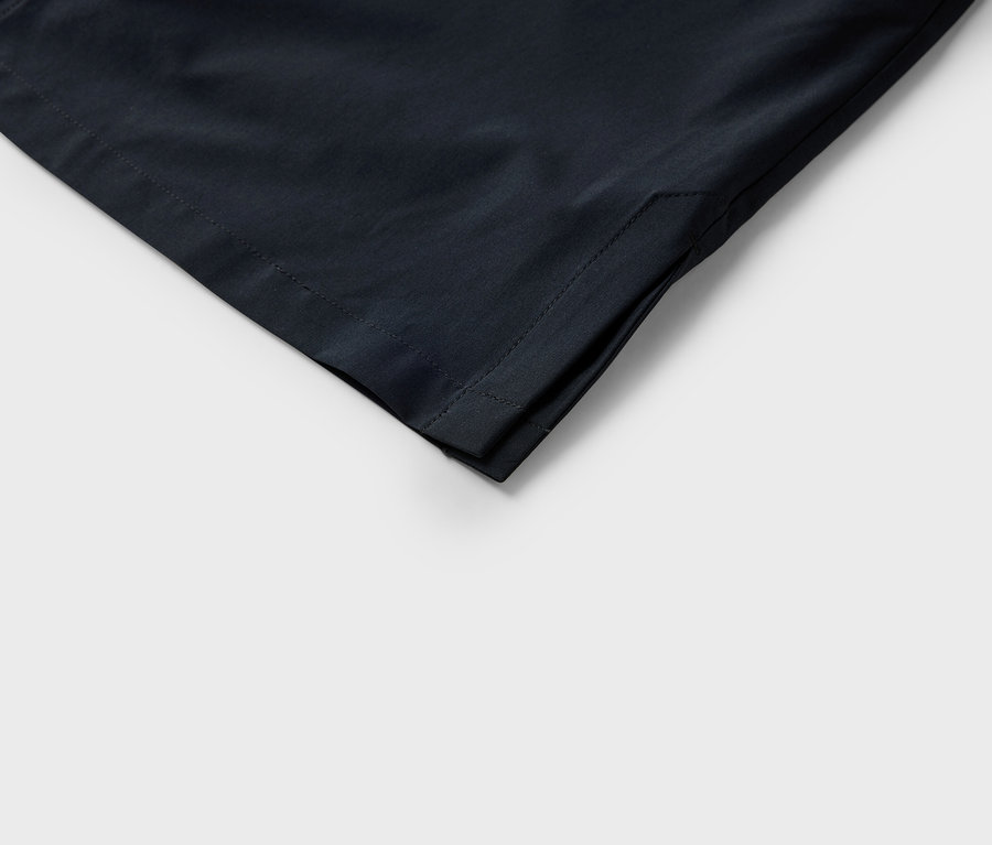 Koyu renkli bir kumaşın dikişleri görünen köşesinin yakın çekimi.