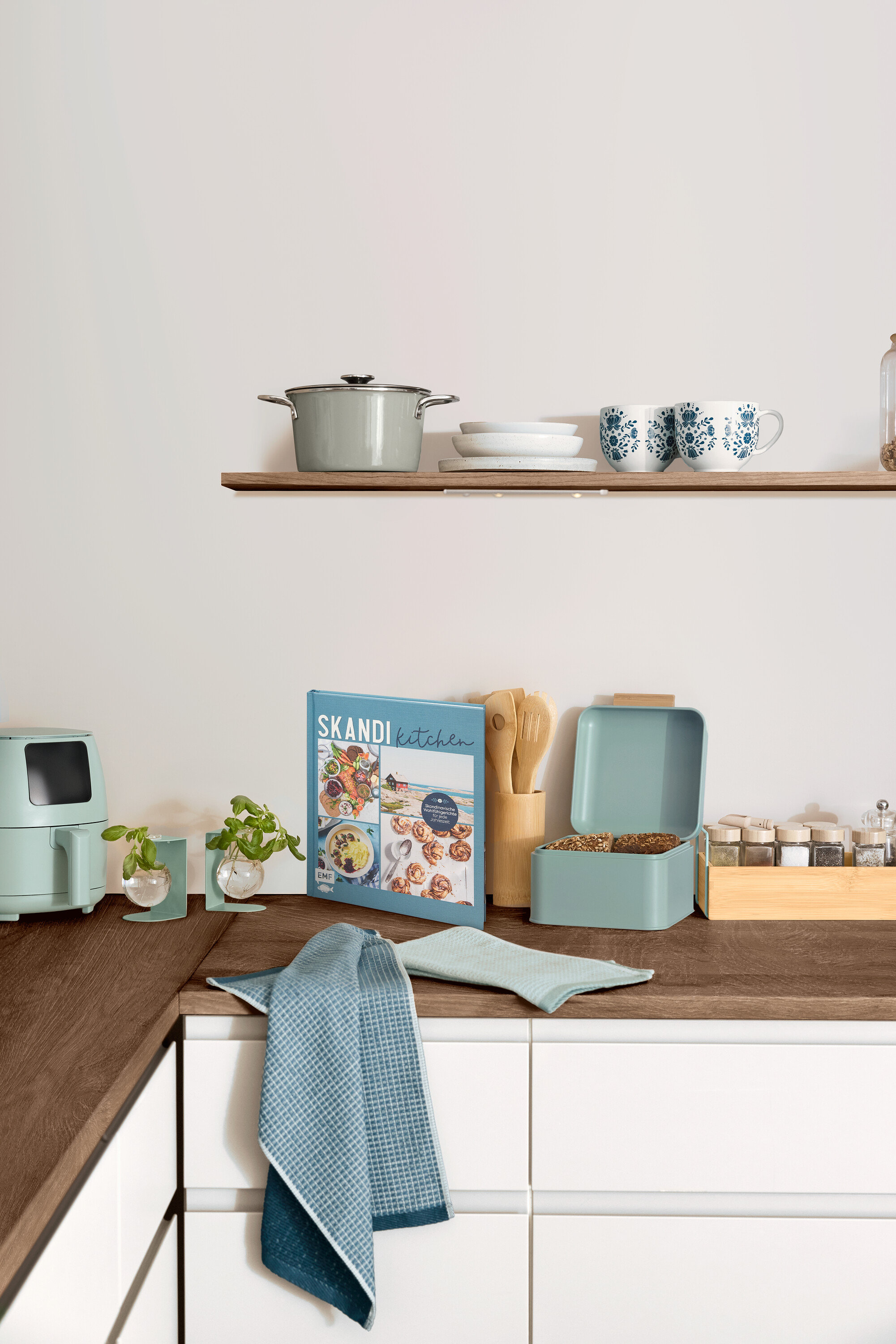 Mutfak tezgahında yemek kitabı, bulaşık ve mutfak gereçlerinin bulunduğu bir mutfak fotoğrafı.