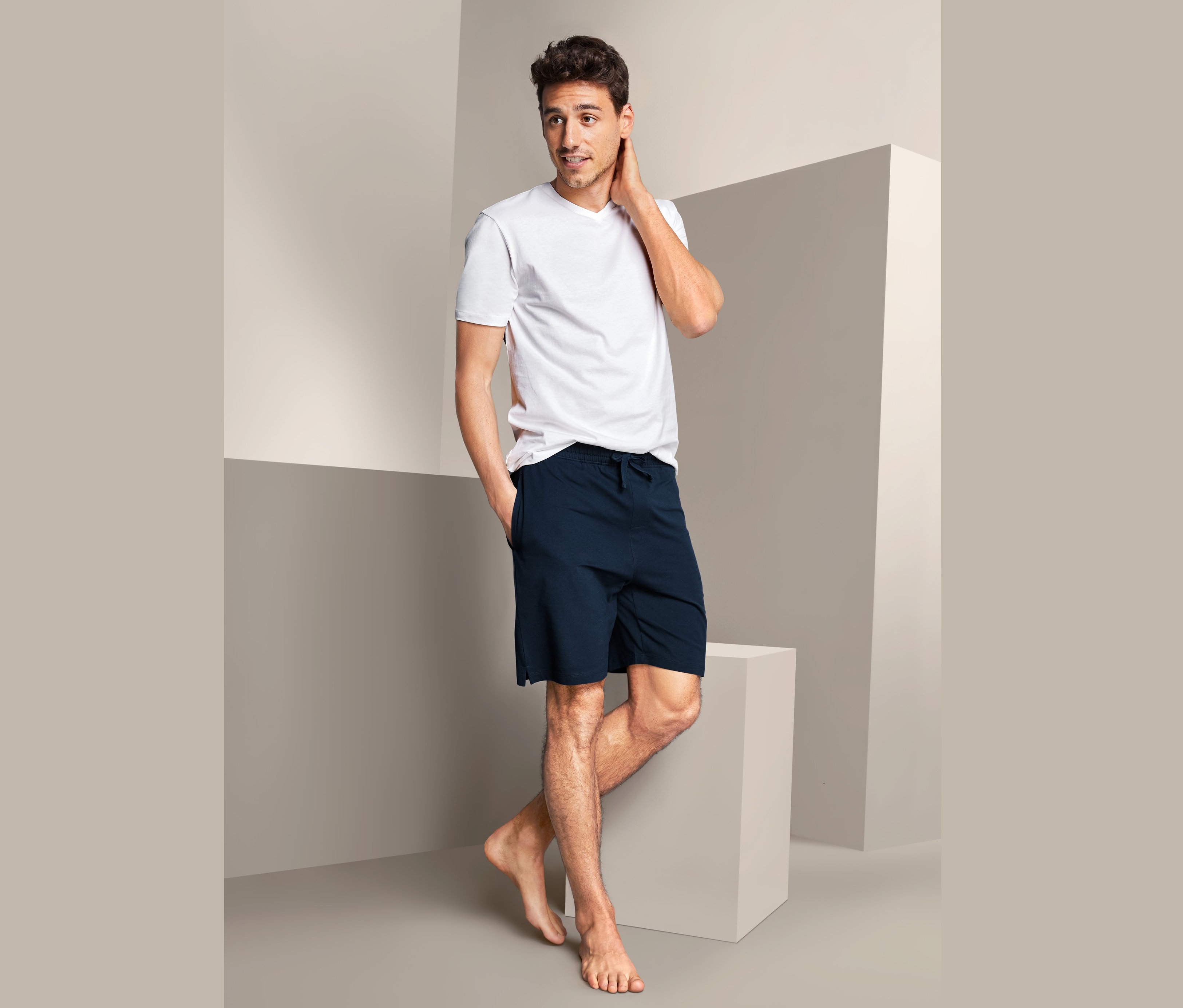 Adam Organik Pamuklu Rahat Şort ve beyaz tişörtle poz veriyor.