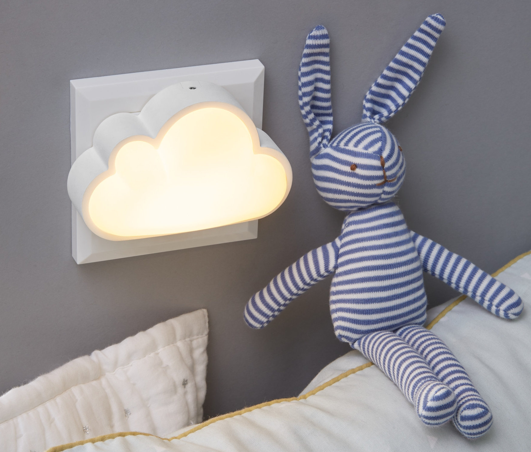 Duvara LED Gece Lambası takılıdır. Yastığın üzerinde peluş bir tavşan oturuyor.