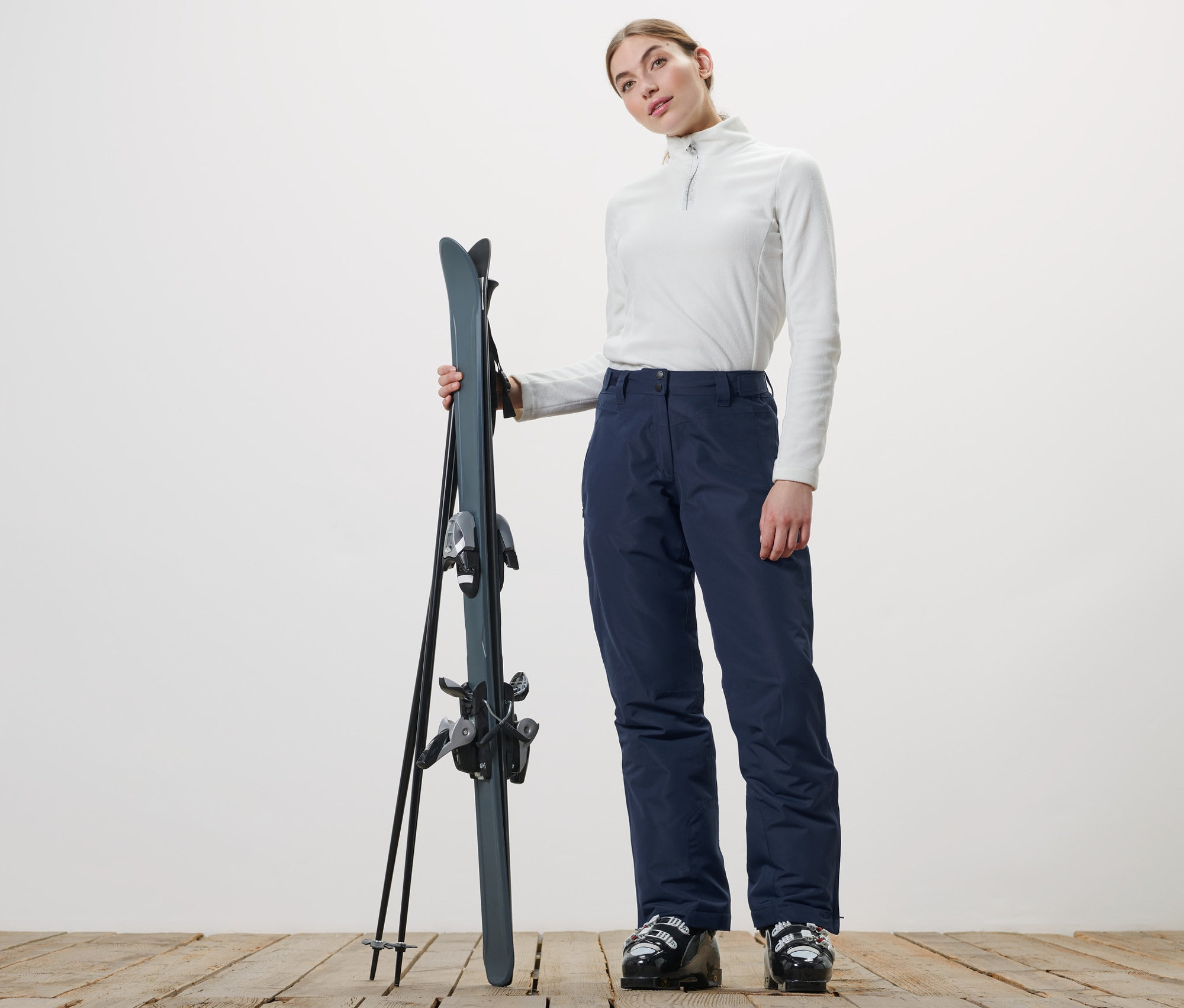 Kadın kayak tutuyor ve Kayak Pantolonu giyiyor.