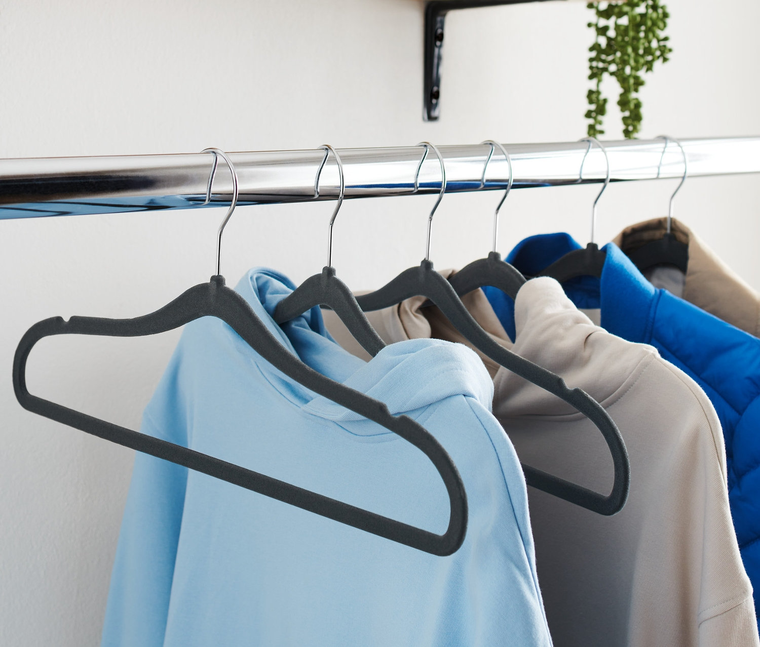 Dört adet askıdaki giysi bir çubuğa asılı duruyor. Askılar 6 Adet Ekstra İnce Kıyafet Askısı, Siyah.