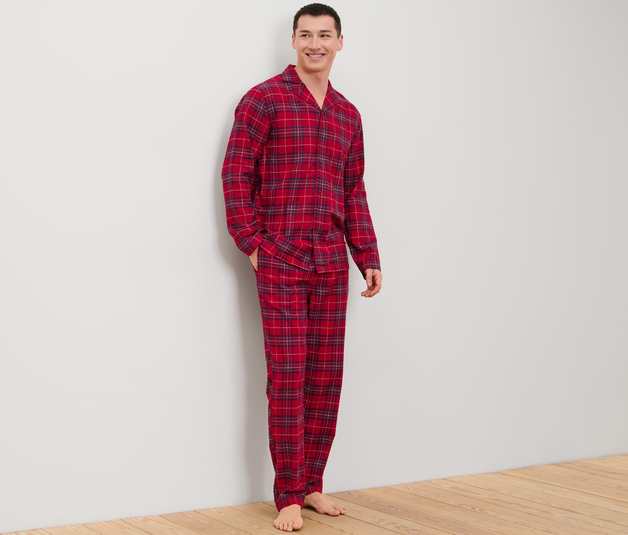 Bir adam ayakta duruyor ve flanel pijama takımı giyiyor.