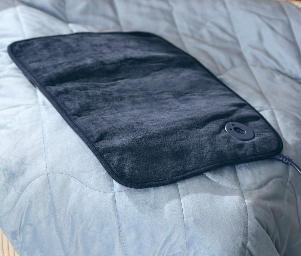 Isıtıcı botlar ve küçük ısıtıcı yastık, 6 kg ağırlığındaki rahatlatıcı ağırlıklı battaniyenin üzerinde duruyor.