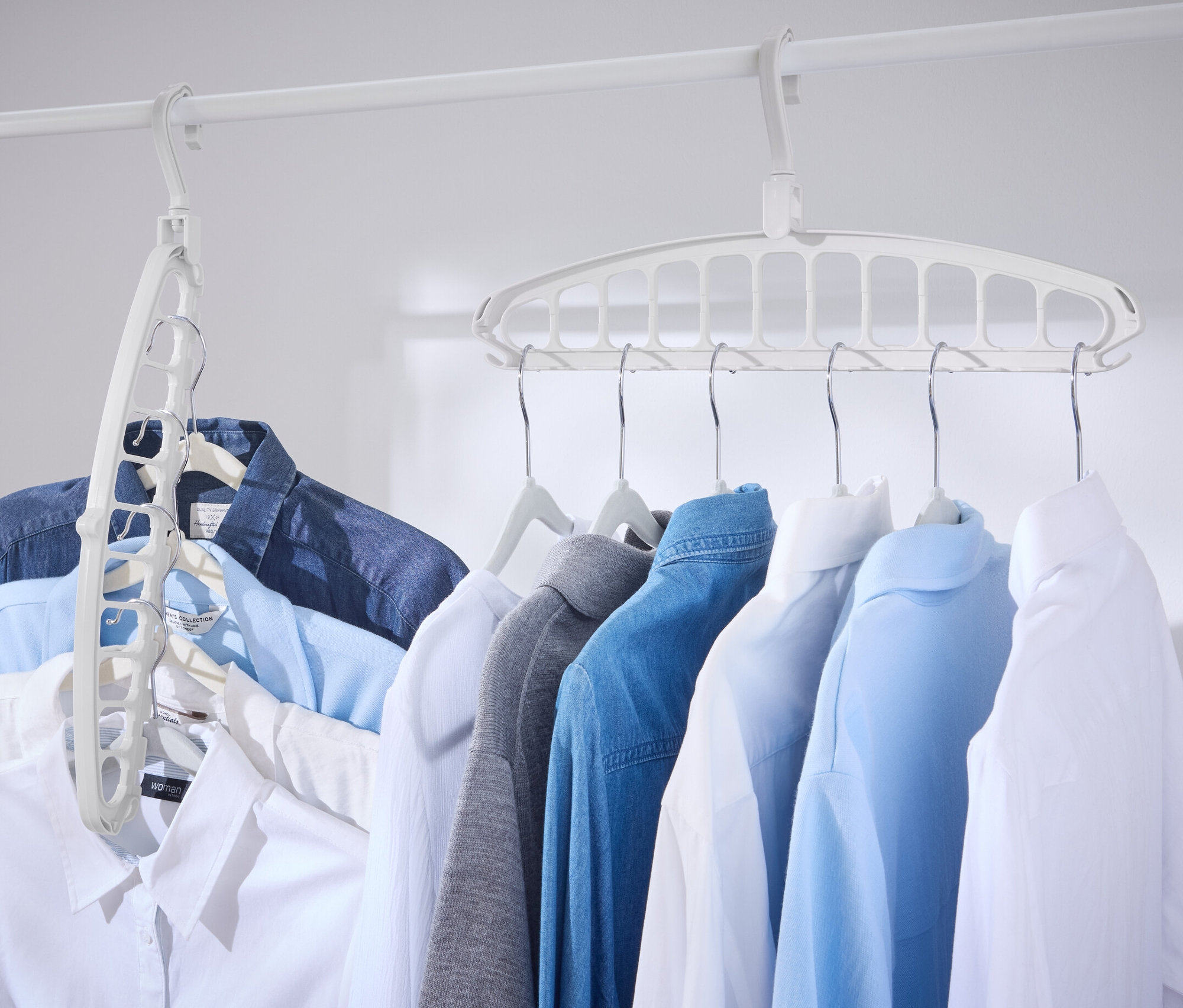 Beyaz bir çubukta, 2 adet çok fonksiyonlu askı ile asılı duran birkaç gömlek var.