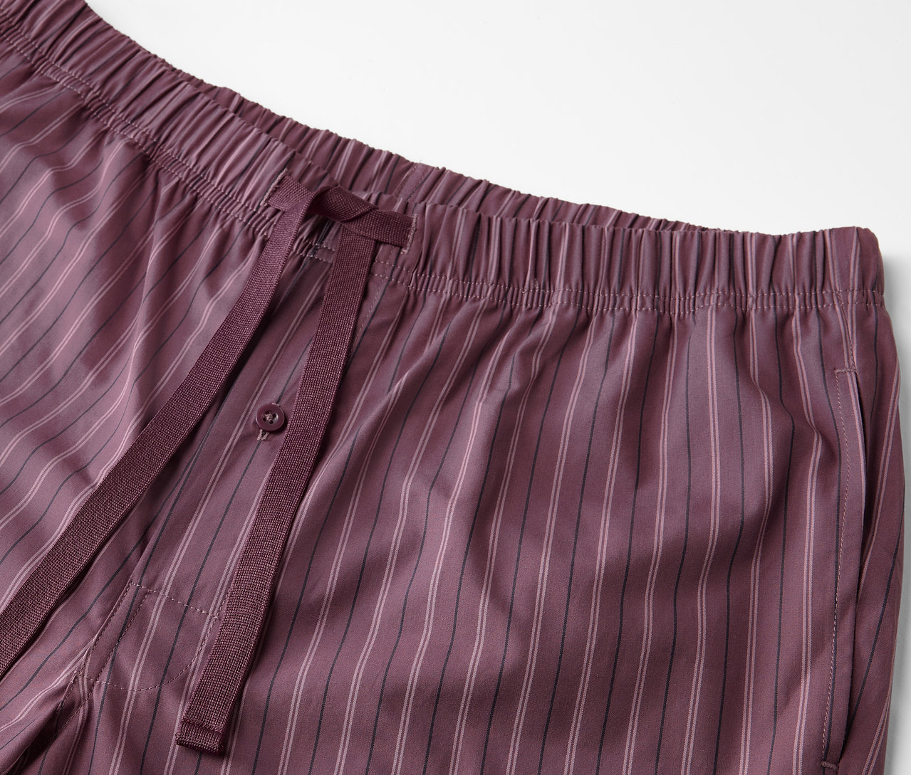 Dokuma desenli ve bağcıklı bordo renkli bir pijama altının yakın çekimi.