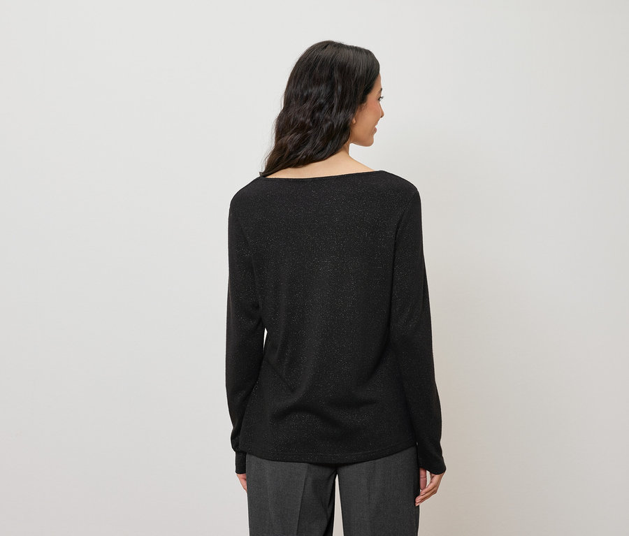 Arkadan, koyu renk saçlı, parıltılı siyah, uzun kollu bir bluz giyen bir kadın görünüyor.