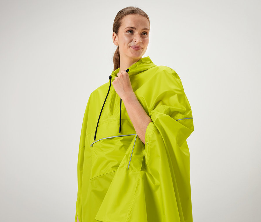 Kadın neon yeşili pançosunun yakasını tutuyor.