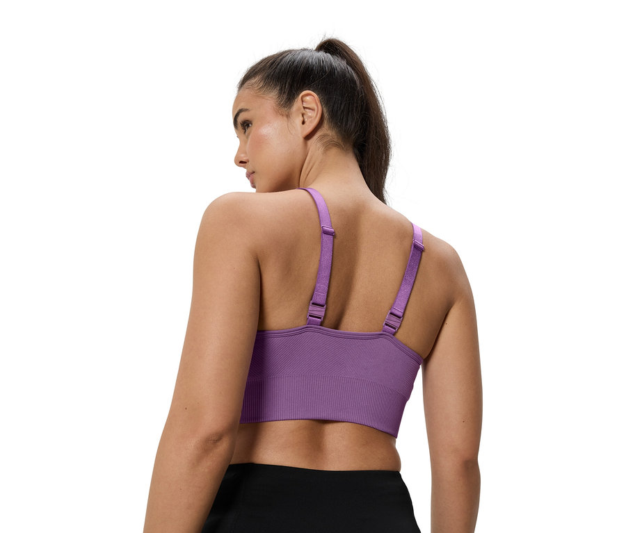 Kadın mor bir spor sütyeni giyiyor.