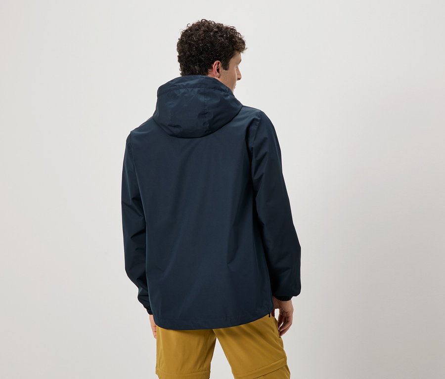 Kıvırcık saçlı bir adamın kapüşonlu lacivert bir yağmurluk ve hardal rengi pantolon giydiği arka görünümü.