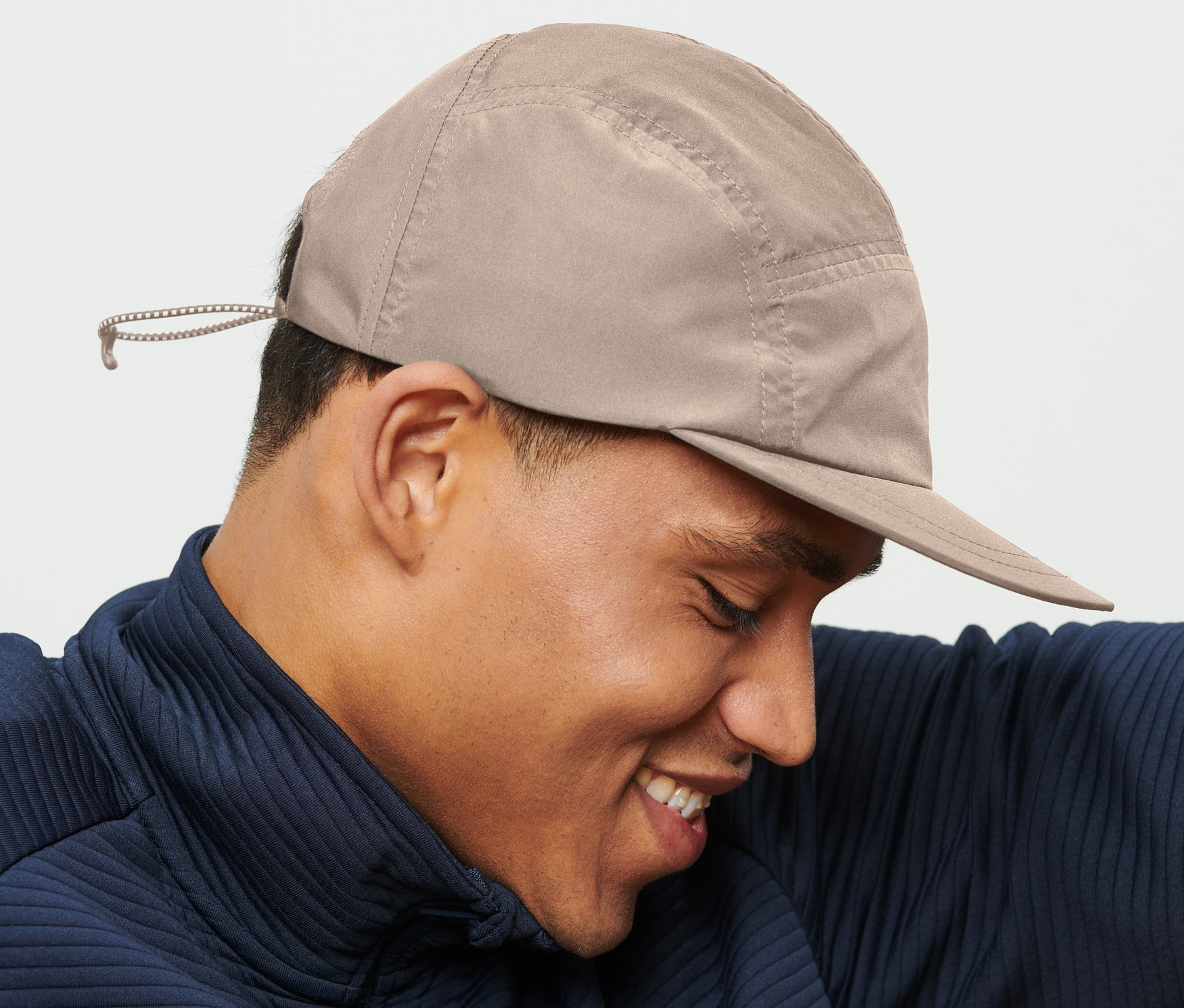 Bej rengi kep şapka takan gülümseyen adam.