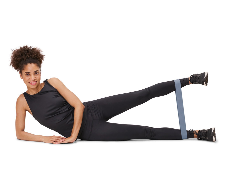 Bir kadın yan yatıyor ve bacaklarının etrafında 3 Adet Antrenman Bandı ile egzersiz yapıyor.