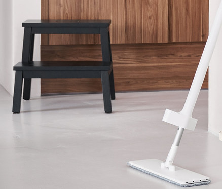 Yerde sprey fonksiyonlu paspas, yanında katlanabilen temizlik kovası duruyor. Arka planda 2 basamaklı merdiven tabure.