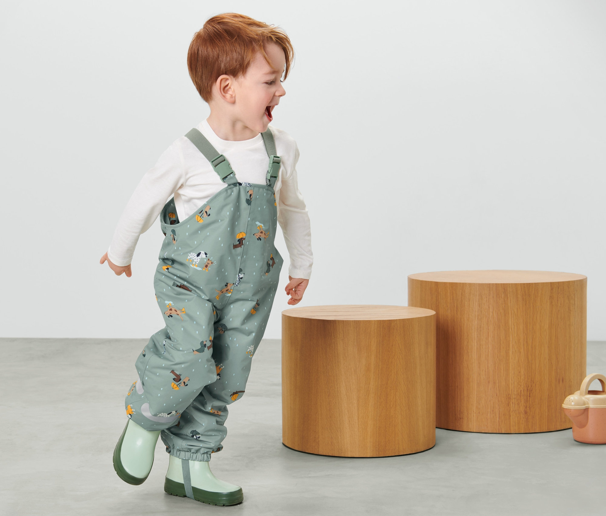 Köpek desenli çocuk termal yağmur pantolonu ve lastik çizme giyen erkek çocuk.