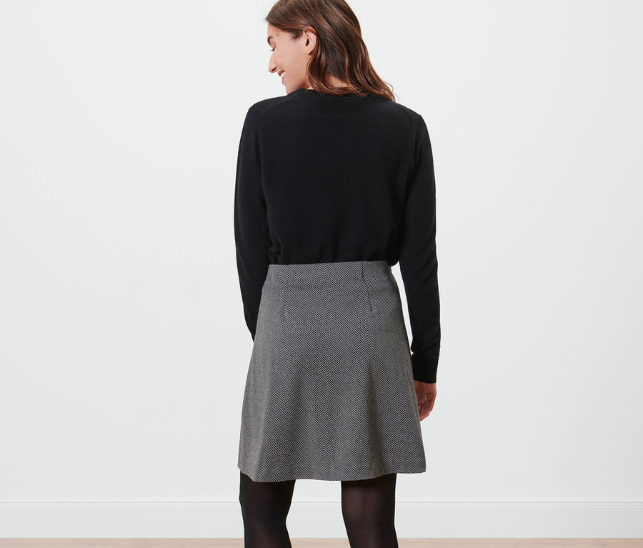 Kadın siyah bir kazak ve Sweat Etek giyiyor.