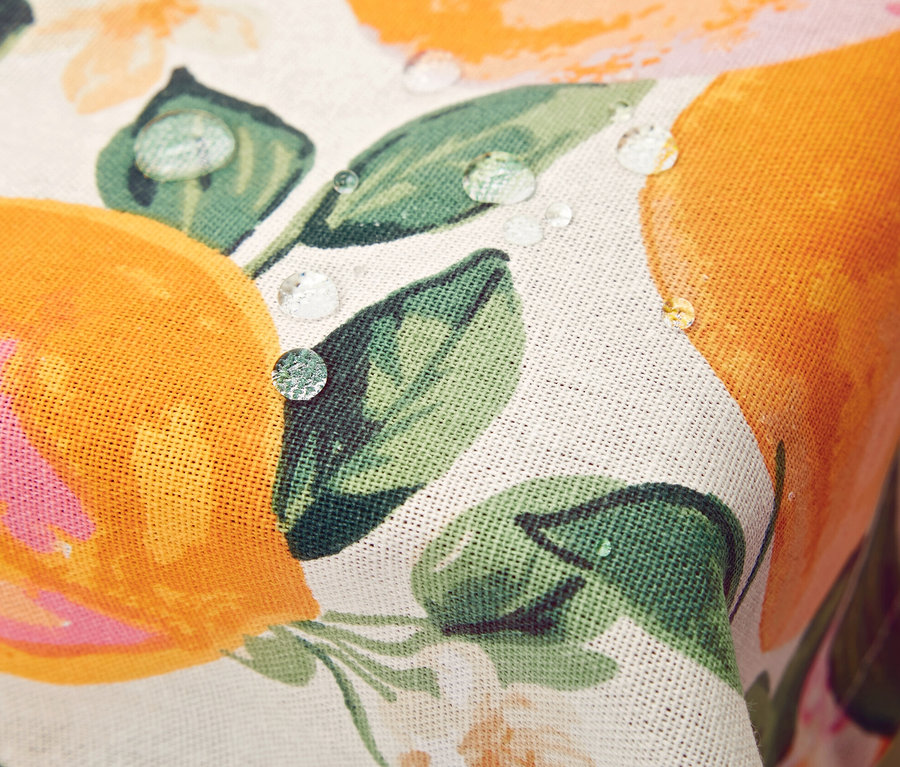 Üzerinde su damlaları bulunan, portakal ve çiçek desenli silinebilir masa örtüsü detayı.