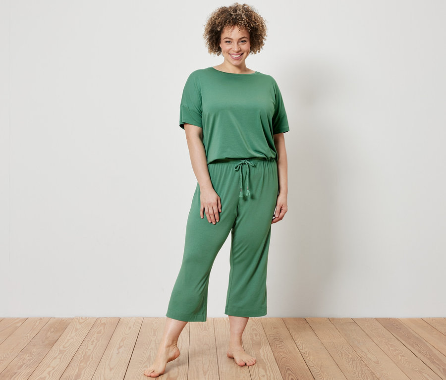 Kadın yeşil renkli 3/4 pijama takımı giyiyor