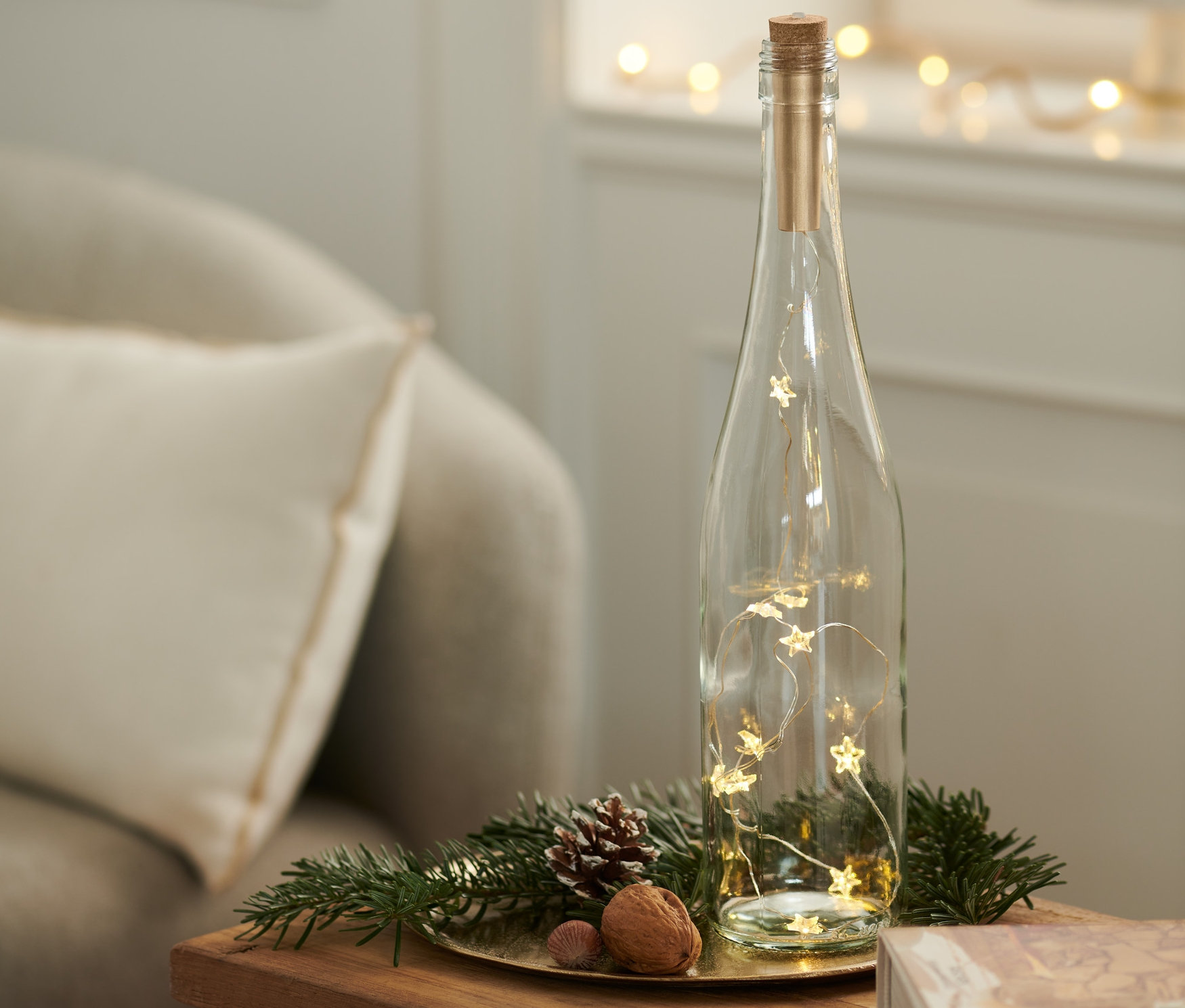 LED'li şişe mantarı olan cam şişe, masanın üzerinde bir kitabın yanında duruyor.