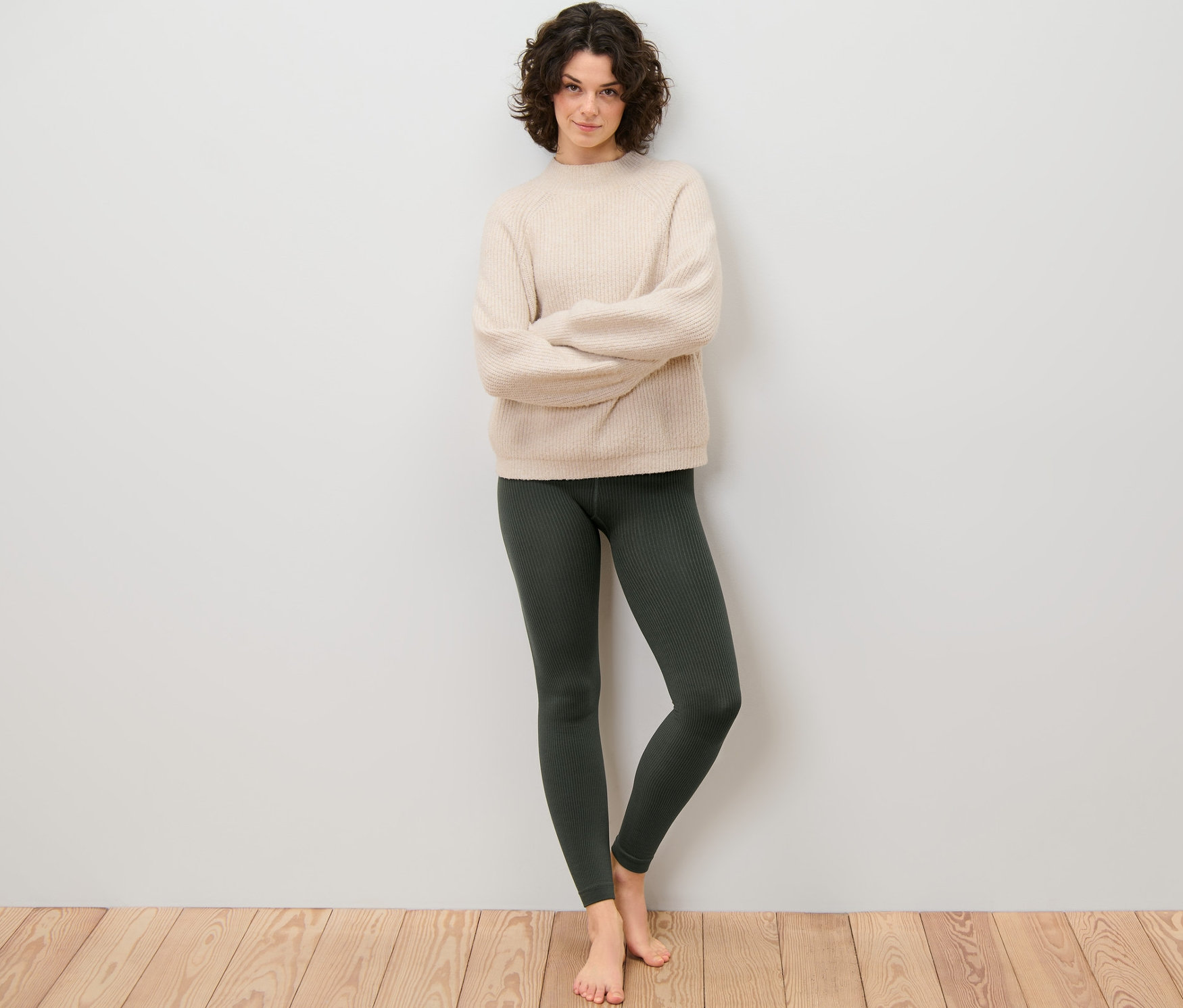 Kadın kolları çapraz bir şekilde duruyor ve fitilli termal tayt giyiyor.