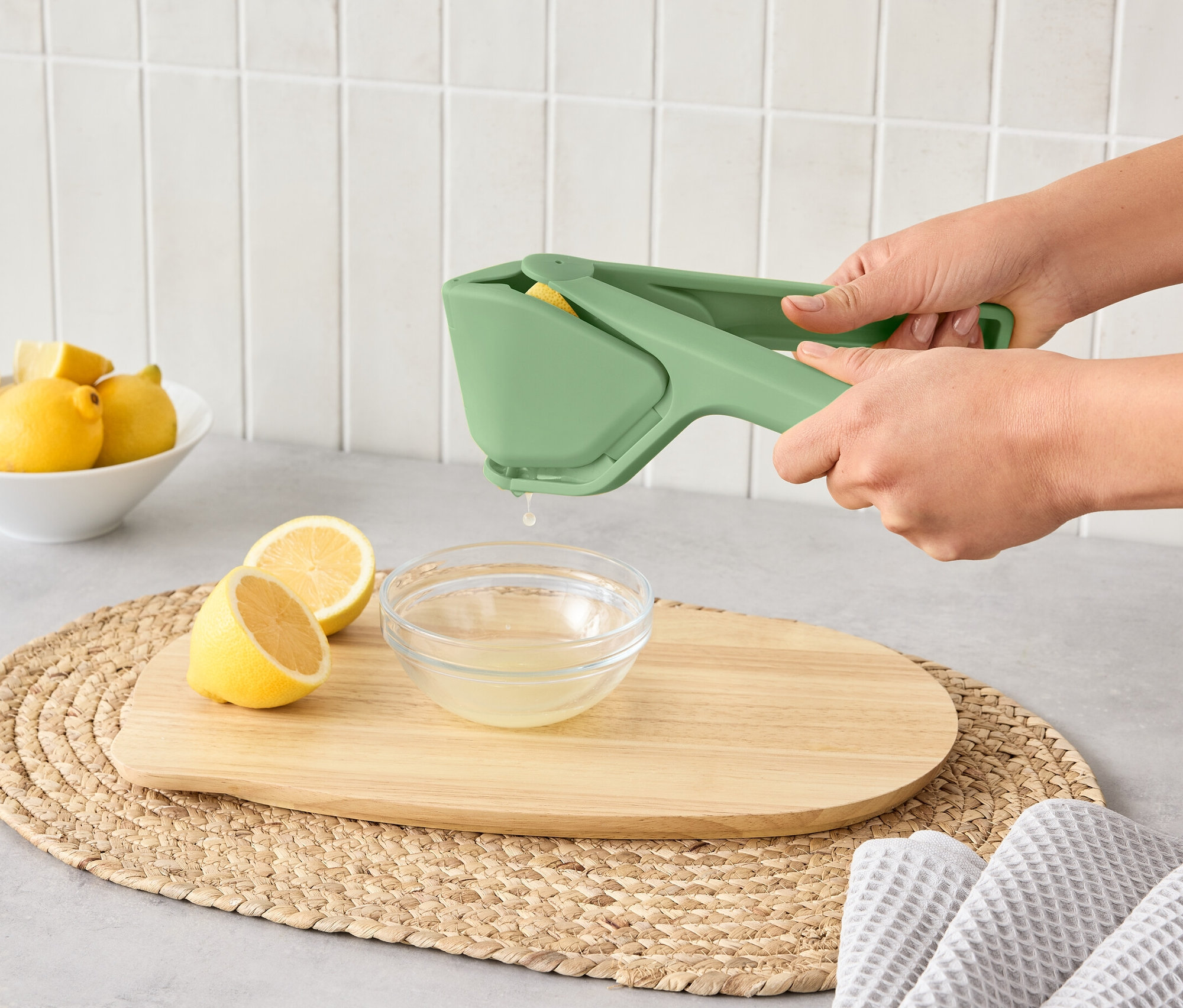 Kadın, yer kaplamayan narenciye sıkacağı ile bir limonu bir kaseye sıkıyor.