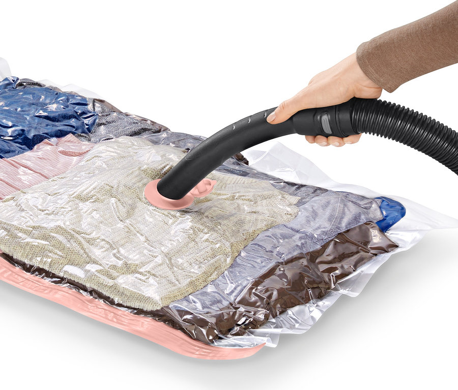 Bir el, 2 adet yatay vakumlu saklama torbası üzerinde bir elektrikli süpürge hortumu kullanıyor.