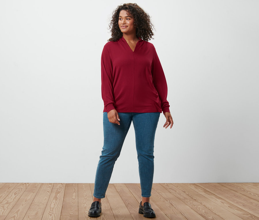 Kadın bordo uzun kollu V yaka bluz, Fit Nelly treggings ve deri loafer ayakkabı giyiyor.