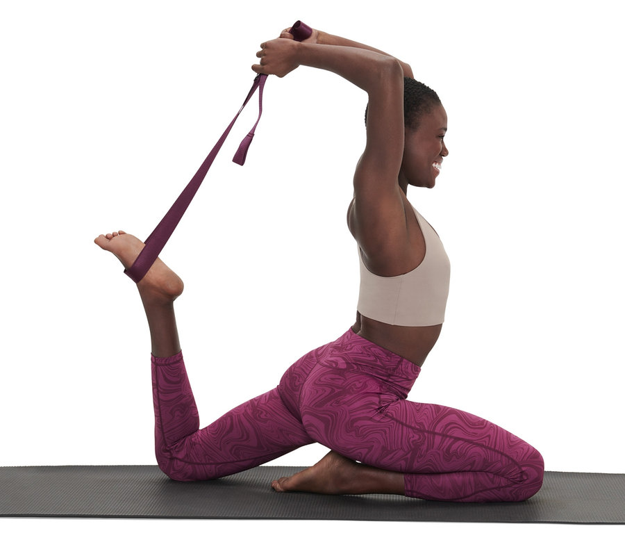 Kadın, bir mat üzerinde gerinirken mor renkli 2'si 1 arada yoga kemeri kullanıyor.