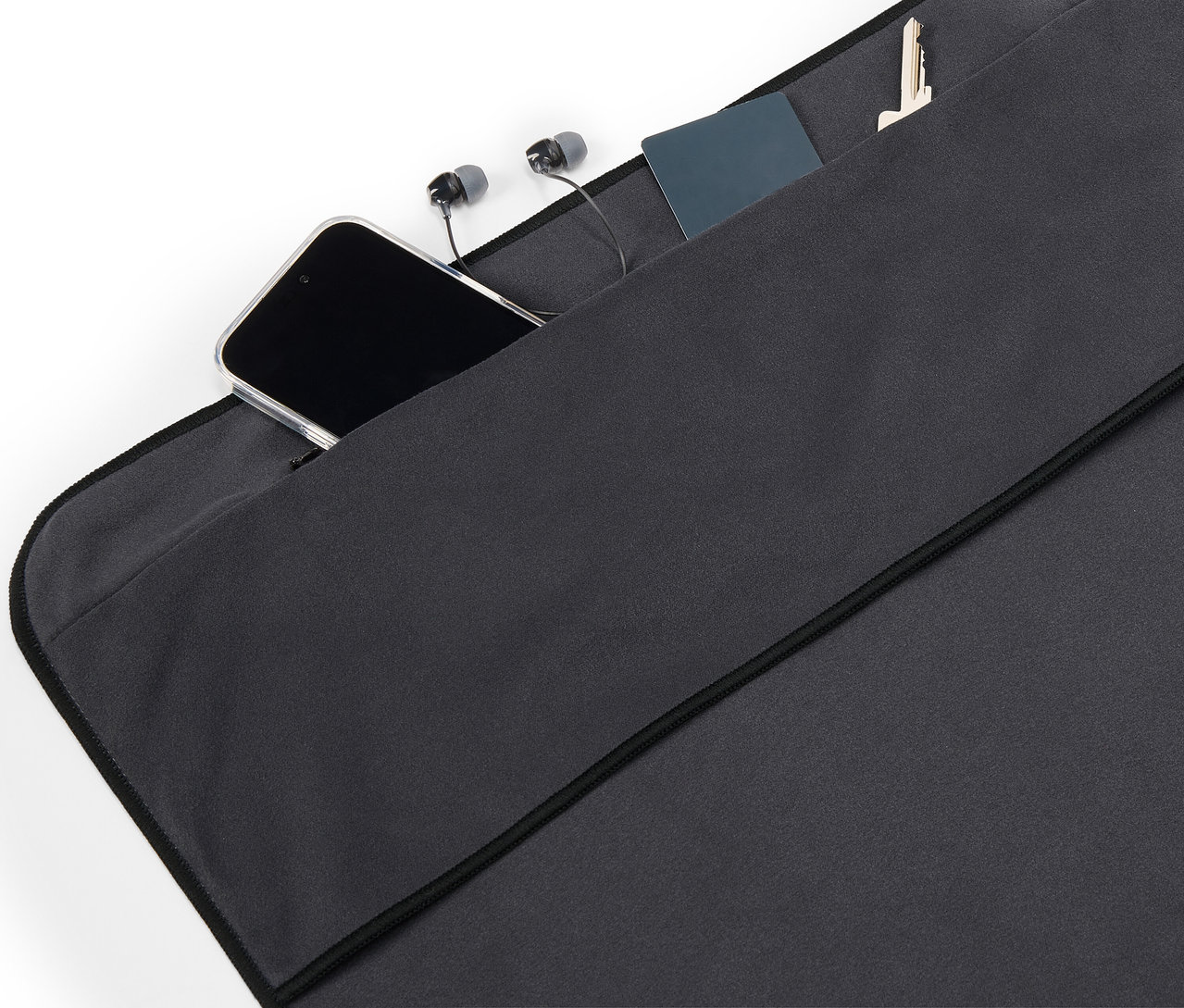 Siyah kumaş ceplerde bir cep telefonu, kulaklık, kart ve anahtar duruyor.