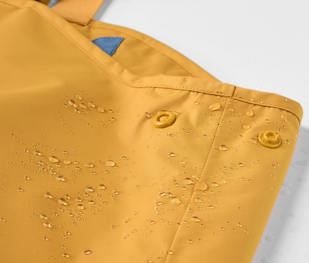 Su damlaları olan çocuk yağmur pantolonunun detayı.