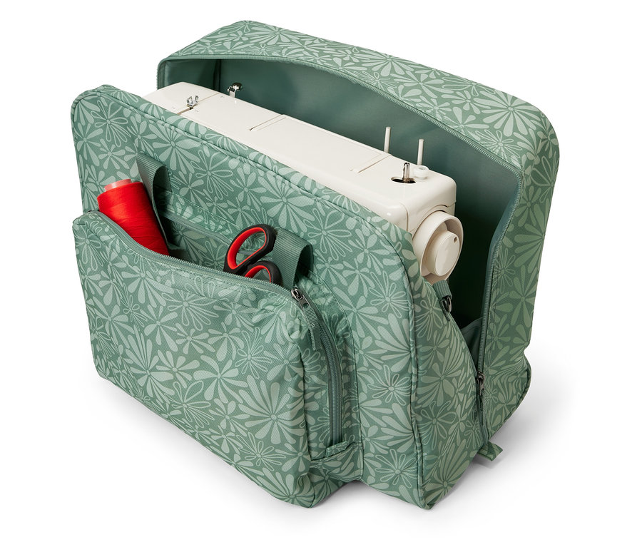 Çiçek desenli, içinde dikiş makinesi, kırmızı iplik bobini ve makas bulunan açık dikiş makinesi çantası.