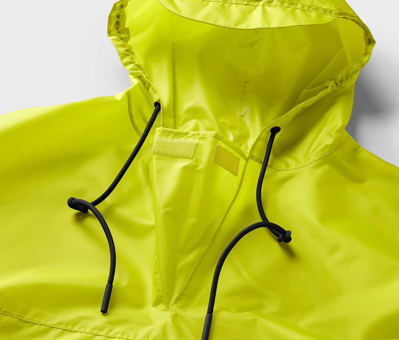 Kapüşonlu ve siyah büzgülü ipli neon sarısı bir yağmurluk yakın çekimi.