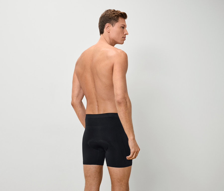 Üstsüz, siyah boxer şort giyen bir adamın arka görünümü.