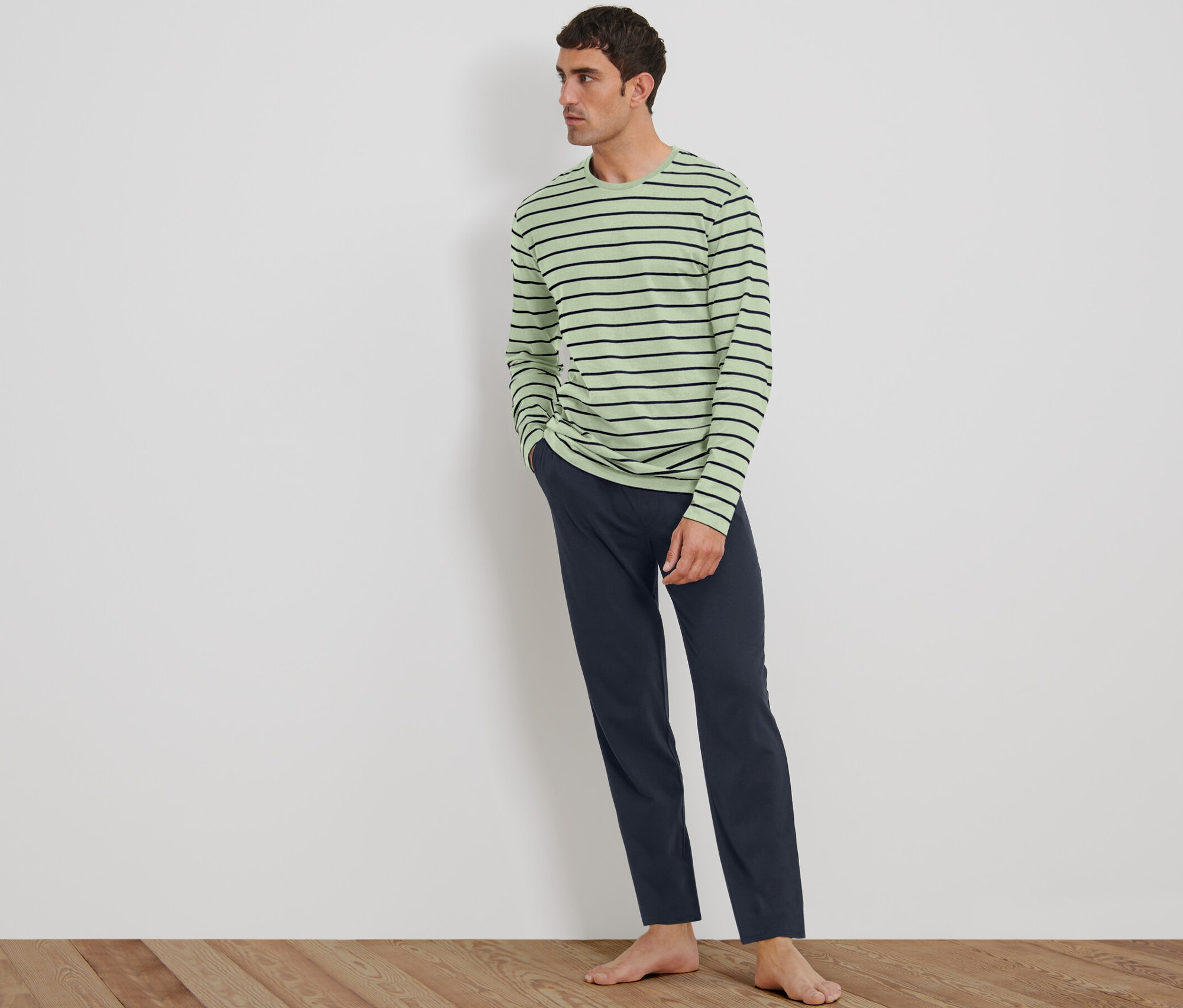 Ayakta duran bir adam yeşil-lacivert pijama takımı giyiyor.