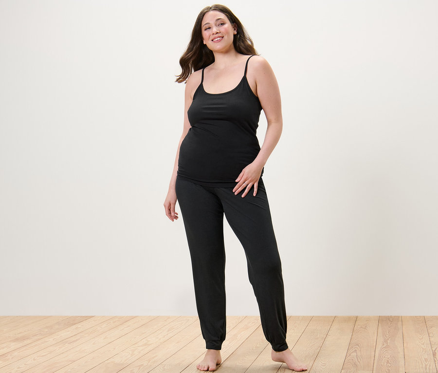 Kadın Pijama Altı ve 2 Adet İp Askılı Atlet giyiyor.