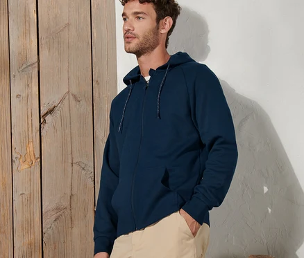 Lacivert fonksiyonel sweatshirt ceket ve bej pantolonlu bir adam poz veriyor