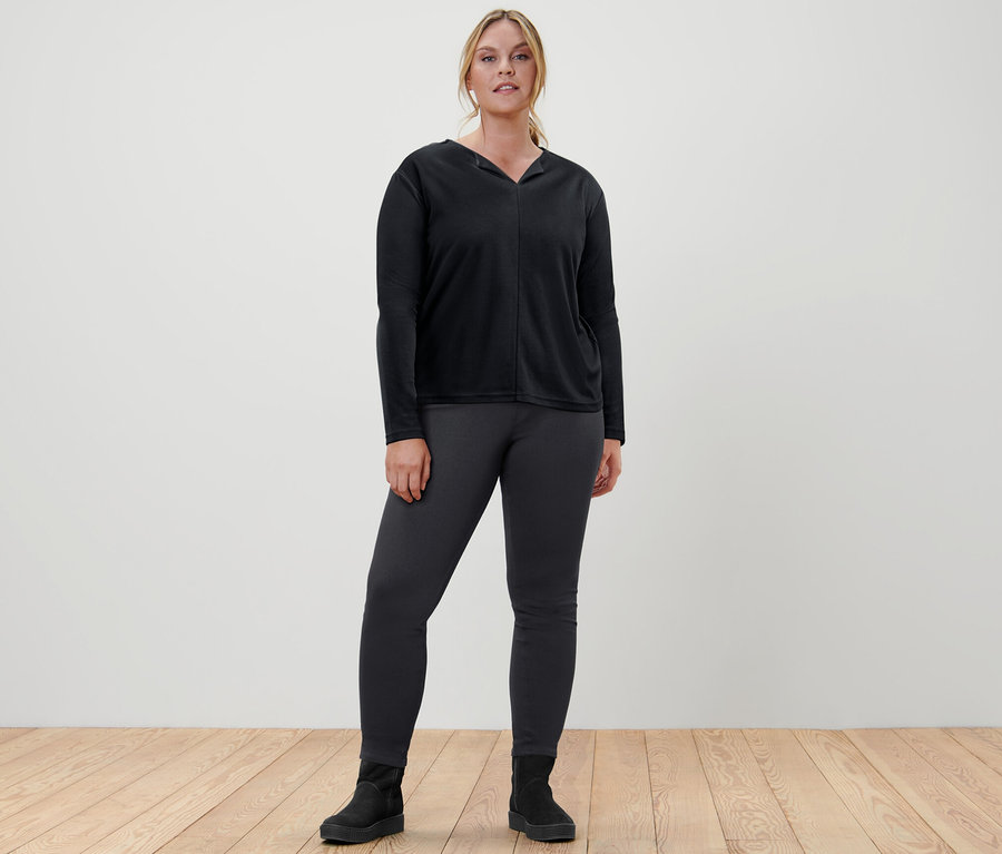 Kadın siyah bluz ve jegging pantolon giyiyor.