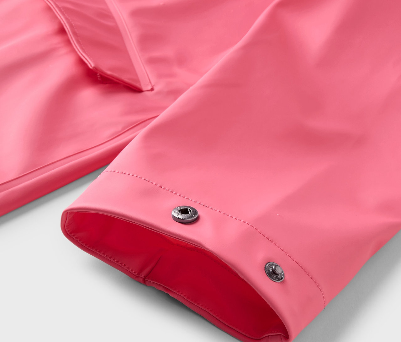 Çıtçıtlı pembe bir yağmurluğun yakın çekimi.